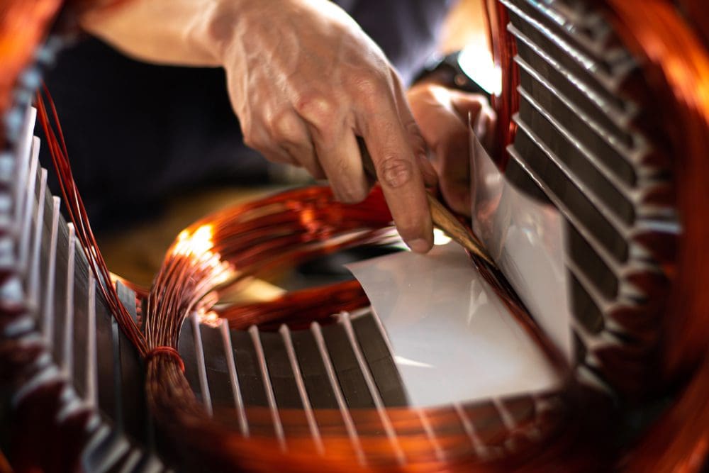Hand working on motor coil winding